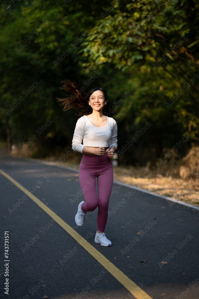 Cheerful woman enjoys jogging on the street in the warm morning sun.