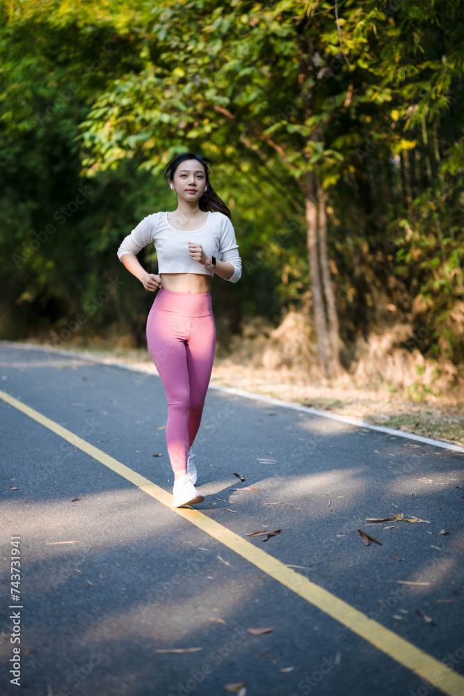 Cheerful woman enjoys jogging on the street in the warm morning sun.