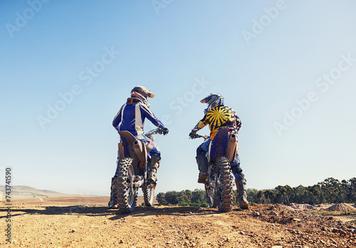 Rear view, sport or people on motorcycle outdoor on dirt road with relax after driving, challenge and competition. Sports, motorbike and dirtbike driver with helmet on offroad and path for racing photo