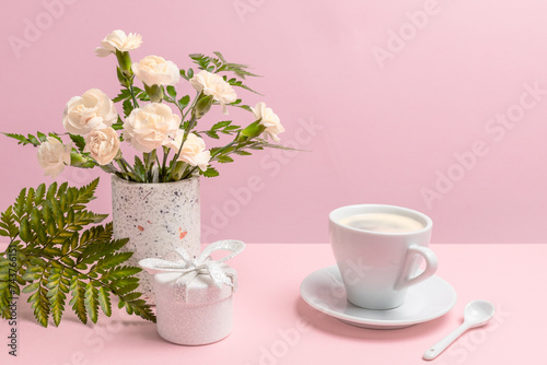 Bouquet of carnations in a vase with a gift box and a cup of coffee. © Vitalii M