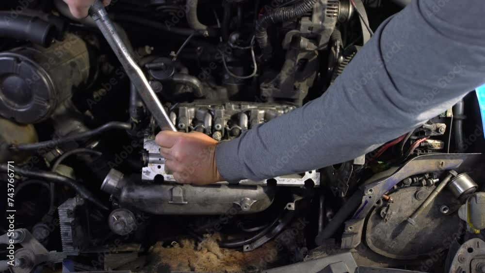 Car service in a car service center. An auto mechanic tightens an engine bolt with a torque wrench. Car engine repair. Car service in a car service center. An auto mechanic tightens an engine bolt with a torque wrench. Car engine repair.