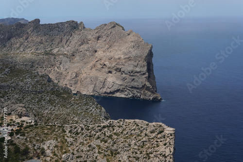 View of the coast of island. Sea and rocks. A rocky cliff washed by the blue ocean below. Majorca, Spain. Summer day. Rocks covered in greenery. photo