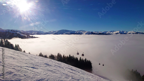 Ski Resort and beautiful sight of alps with lower clouds underneath a clear blue and sunny sky. Lots of fog and mist in the valley of Westendorf, Austria (Tirol).