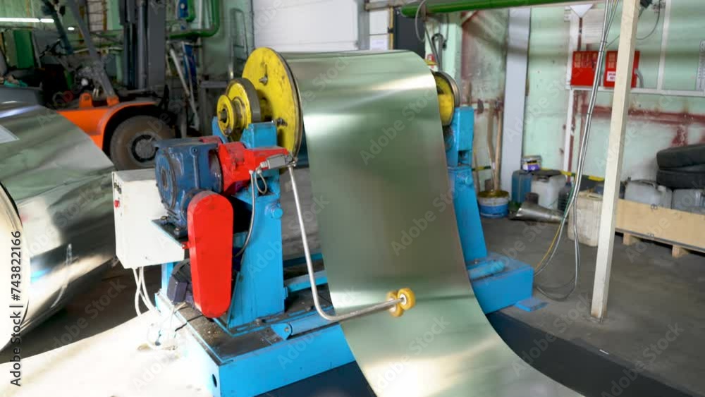 The machine feeds the metal belt onto the conveyor. Interior of a metalworking workshop. Modern industrial enterprise. The machine feeds the metal belt onto the conveyor. Interior of a metalworking workshop. Modern industrial enterprise.