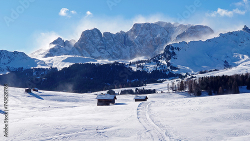 Ski Resort Alpe di Siusi in Italy (Val Gardena) during a heavy storm on a sunny day on top of the mountains. Beautiful blue sky with snowstorm above the Dolimites mountains.