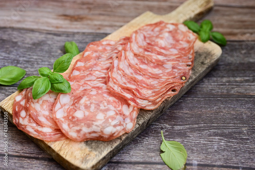 Slices Of  Traditional Italian  dried thinly sliced   artisan  pork salami Milano .Antipasti  salami on a wooden  cutting board