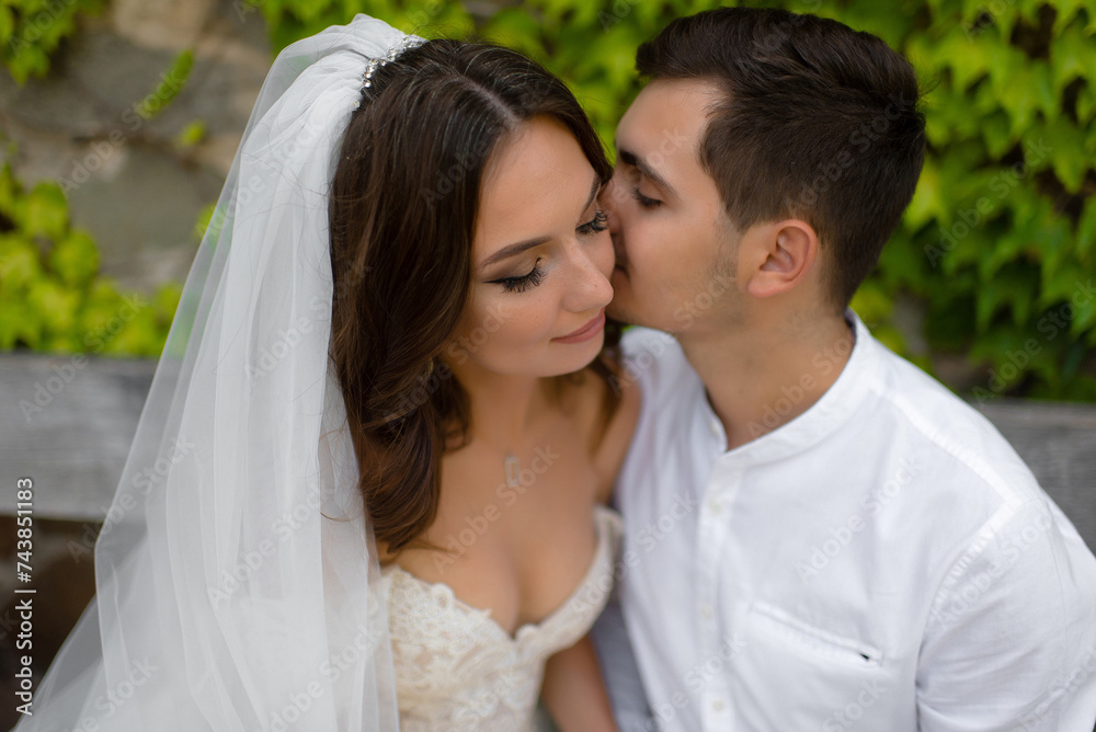 European couple in their 20s embraces; groom lovingly kisses the bride European couple in their 20s embraces; groom lovingly kisses the bride