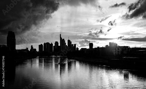 Panoramic view of Frankfurt skyline in Germany. Financial district in downtown with tall bank office buildings. Evening sky with clouds and reflection in River Main, black and white greyscale.  photo