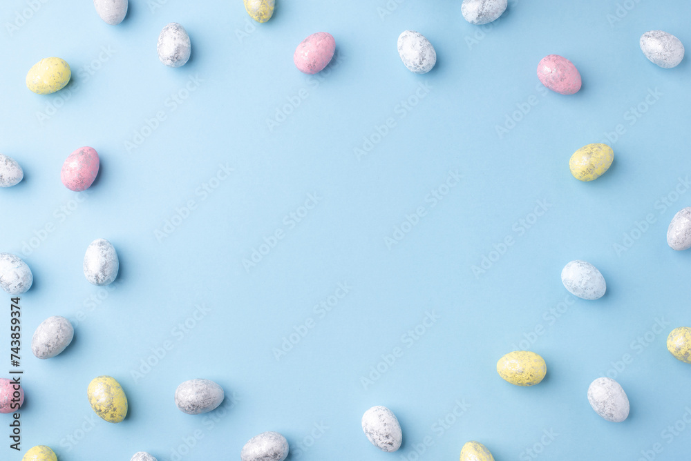 Festive Easter background. Multicoloured Easter eggs on a blue table. Card with a place for text. Top view.