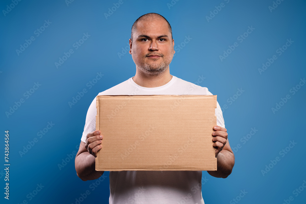 Portrait of a Brazilian man wearing a basic white shirt, from the front, holding a cardboard sign with both hands, serious and looking at the camera - Belém - Pará - Brazil Portrait of a Brazilian man wearing a basic white shirt, from the front, holding a cardboard sign with both hands, serious and looking at the camera - Belém - Pará - Brazil