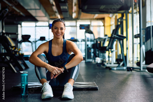 Portrait of happy athletic woman in gym looking at camera.