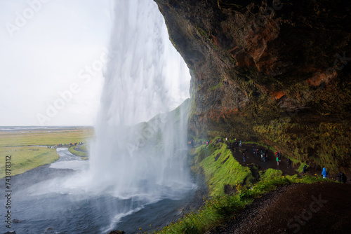 Seljalandsfoss  a famous and unique waterfall in Iceland with visitors walking behind the falls into a small cave. Trip concept.