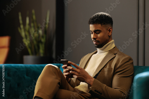 Businessman chilling on the sofa and texting at work