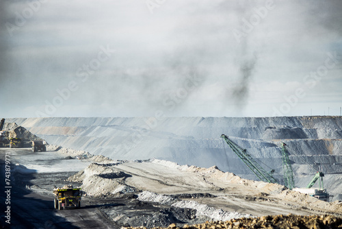 Dump trucks filling up with overburden and dragline in dusty open cut coal mine photo