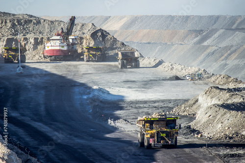 Dump trucks filling up with overburden and carting it through open cut coal mine photo