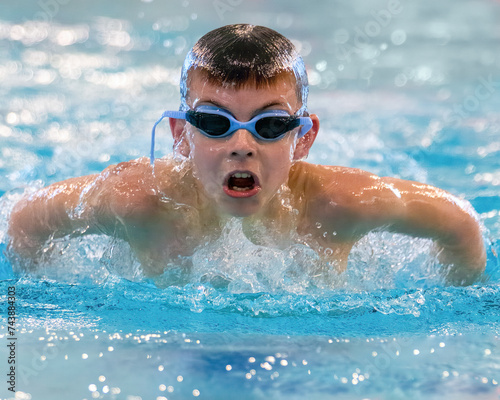 Competitive youth swimmer doing butterfly stroke in pool