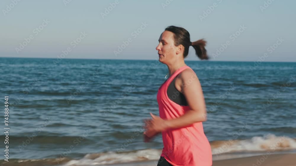 Woman runs along seashore. Morning run on beach. Female jogging along coastline Woman runs along seashore. Morning run on beach. Female jogging along coastline