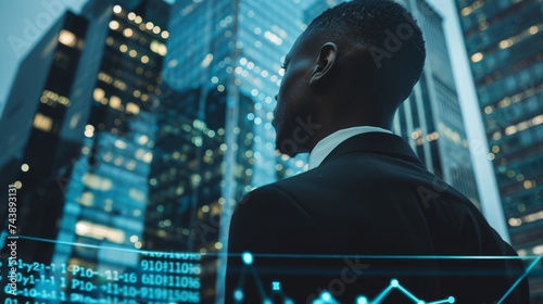 African American businessman in formal wear is watching at New York city skyscraper. Digital interfd. ace with bar diagram and binary code in foregroun photo