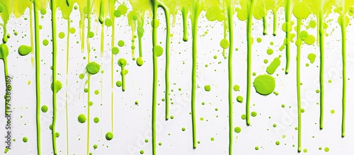 The image captures a white wall with vibrant lime green paint dripping down, creating a playful burst of color against the crisp white backdrop. The drips of paint add an artistic and dynamic contrast photo