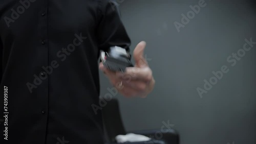 A man in a black shirt rotates and tosses a hair clipper in his hand. The concept of fashionable and stylish haircuts in a barbershop. Slow motion photo