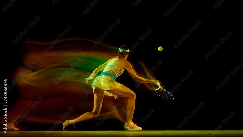 Dynamic photo of young woman preparing to hitting ball against black studio background in motion blur. Fast movement Concept of sport, active lifestyles, tournaments, competition, energy. Ad