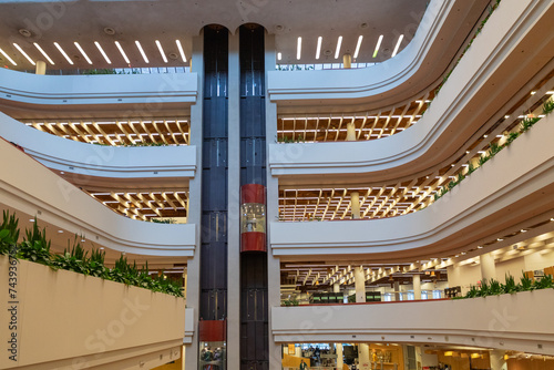 Interior of a public library, with mesmerizing swooping lines and forms, lightfall and colours, with two centred elevators bisecting the lines. photo