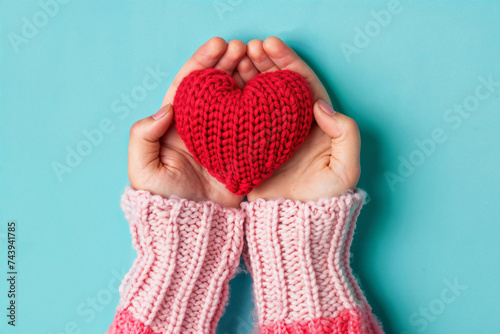 Hands holding knitted heart against blue background. Generative AI