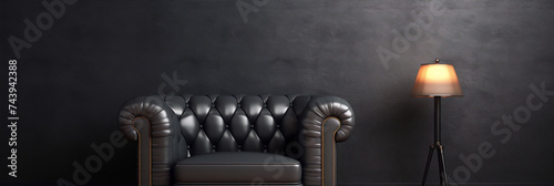 Black leather chesterfield sofa in a dark room with a lamp