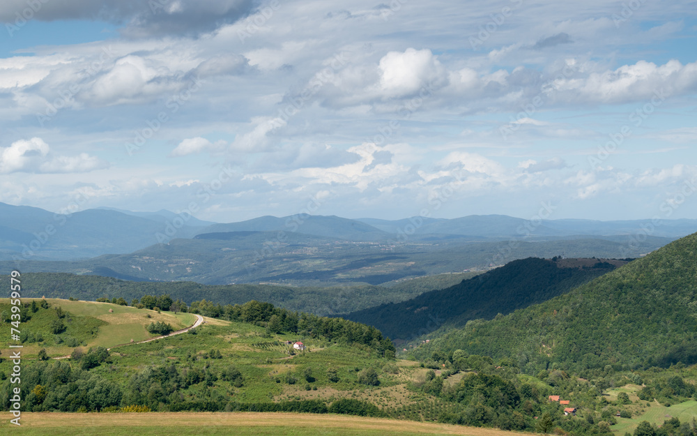 Mountain landscape with farm during cloudy day, cloud shadows on ground Mountain landscape with farm during cloudy day, cloud shadows on ground