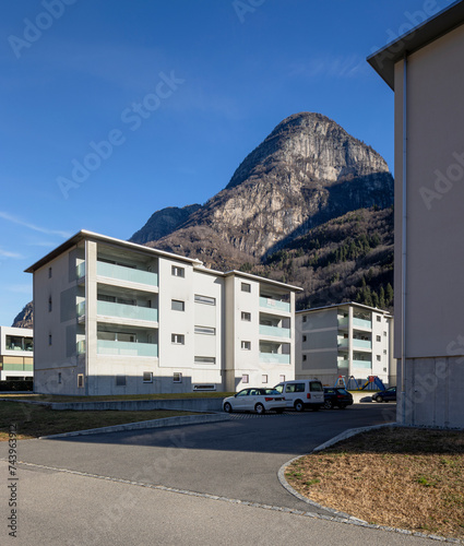 Residential complex with garden and games for children and parking for cars. There is blue sky and mountains behind