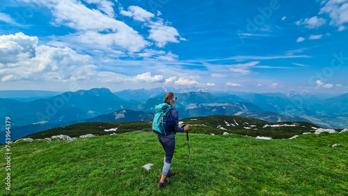 Hiker woman on top of mount Kriznik, Carinthia, border Austria Slovenia. Alpine meadow with scenic view of mountain range Karawanks, Slovenian Austrian Alps. Hiking trail Petzen, Bleiburg, Völkermarkt photo