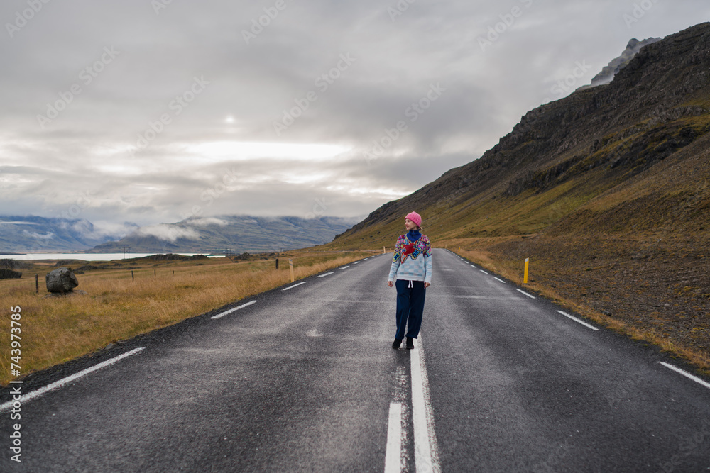 Fototapeta premium Traveling and exploring Iceland landscapes and travel destinations. Young traveler enjoying the view of beautiful nature. Female tourist watching spectacular scenery. Summer tourism by Atlantic ocean