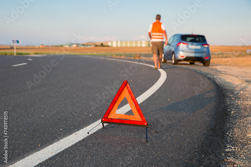 Triángulo de emergencia en la carretera y conductor avisa de un vehículo para en la vía pública photo