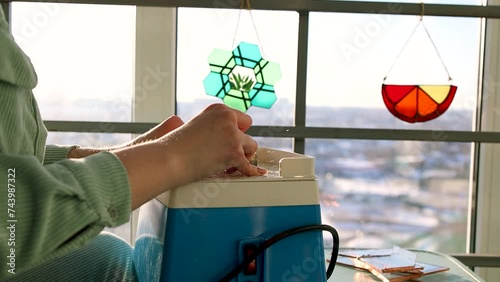 A glass grinding machine. A young woman grinds glass in a workshop. Production of stained glass windows.