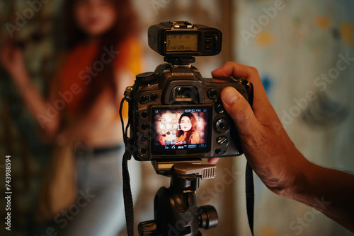 Closeup image of photographer shooting portrait of model with digital camera
