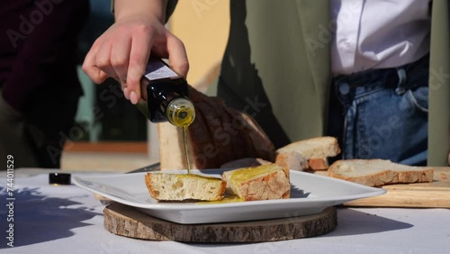 Bruschetta condita con olio extravergine d'oliva.
Primopiano di una fetta di bane bruscato, mentre viene versato l'olio. Tosccana, Lazio, puglia, Liguria. Italia.