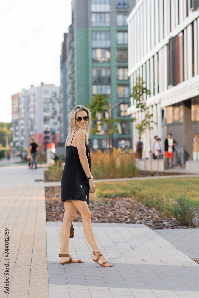 Happy young Caucasian girl in sunglasses walking in the city on a sunny day