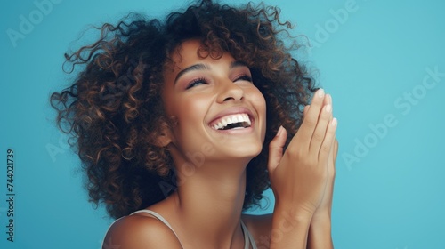 A woman with curly hair smiling and holding her hands to her face. Suitable for various advertising and lifestyle concepts photo