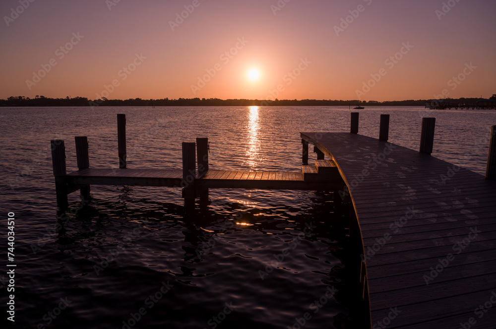 The rising sun centered above a dock on the St. Johns River in Florida The rising sun centered above a dock on the St. Johns River in Florida