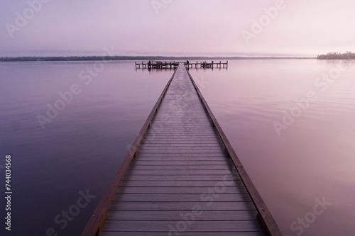 Fototapeta Naklejka Na Ścianę i Meble -  A wooden dock stretching far out into the still water of the St. Johns River on a foggy morning