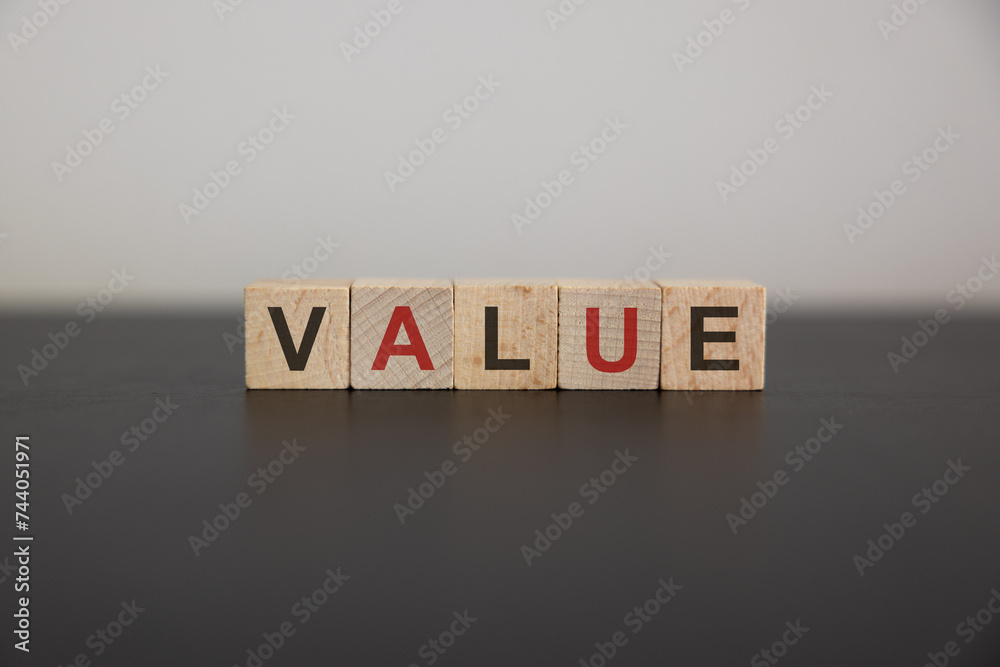 Obraz premium Value symbol. Concept word value on wooden cubes. Businessman hand. Beautiful grey background with succulent plant. Business and value concept. Copy space. Concept word.