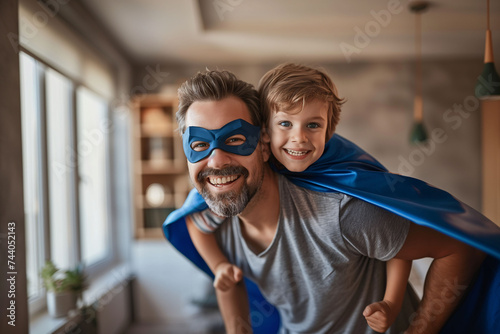 Father carrying his son on his shoulders dressed as a superhero. Father's day.