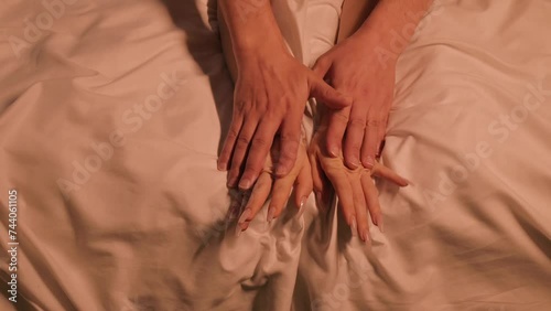 couple in love has sex on a white sheet on the bed at night. Male and female hands during sex