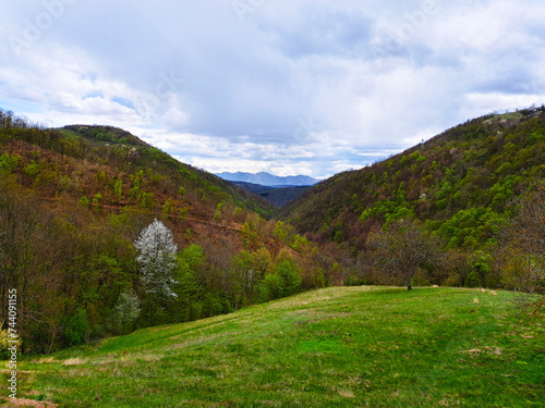 Countryside landscape horizontal photo. Rural scene with hills and mountains in the center at cloudy day