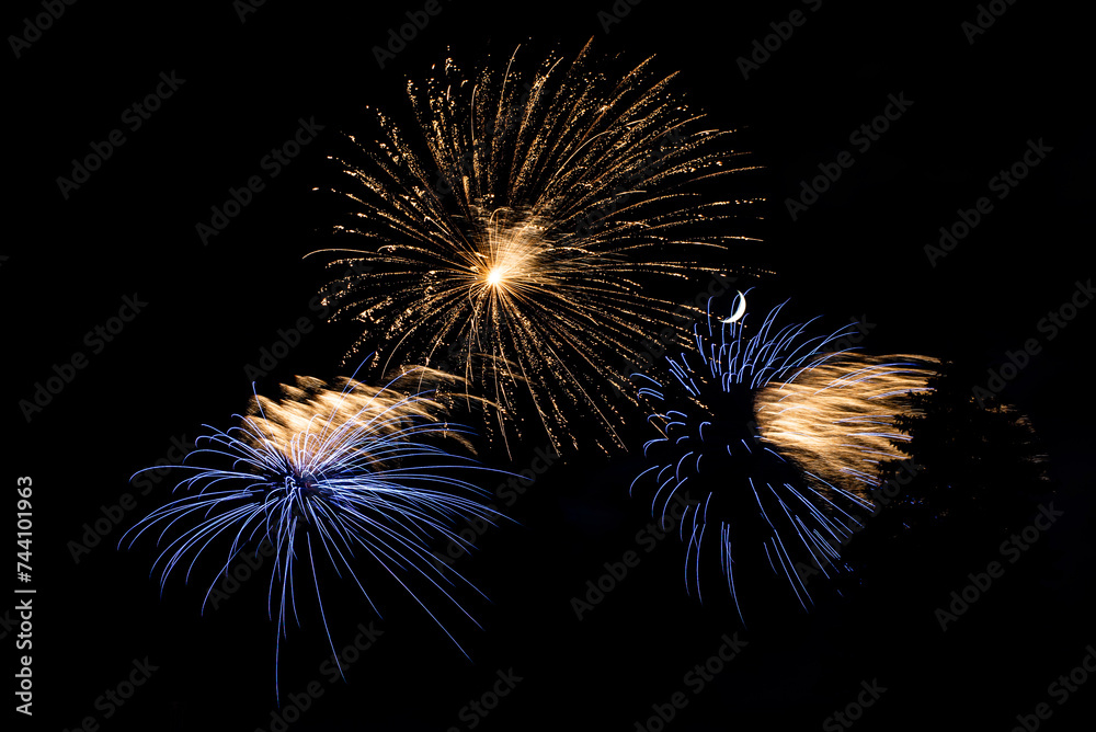 Obraz premium Montreal, Canada - June 25 2022: Fire works show with quarter moon in background at La Ronde in Montreal