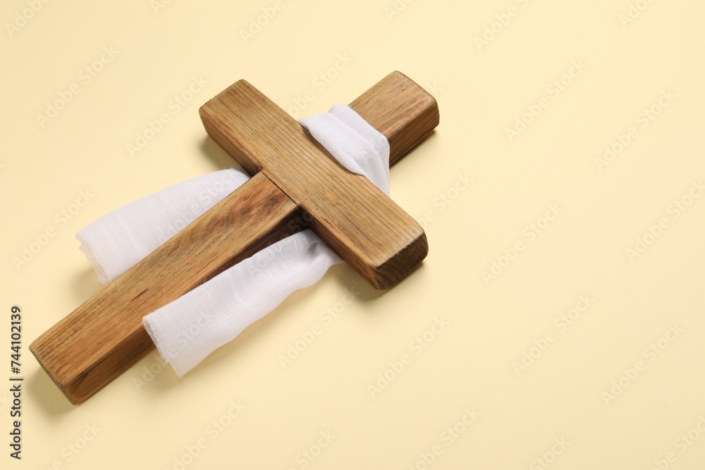 Wooden cross and white cloth on beige background, space for text. Easter attributes Wooden cross and white cloth on beige background, space for text. Easter attributes