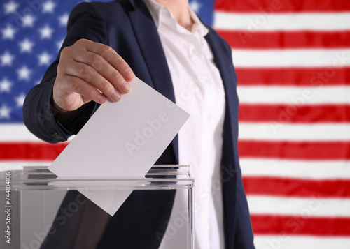 Election in USA. Woman putting her vote into ballot box against national flag of United States, closeup