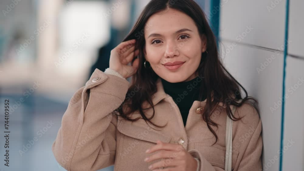 Confident young woman in a stylish beige coat and black turtleneck smiling on an urban blurred background. Confident young woman in a stylish beige coat and black turtleneck smiling on an urban blurred background.