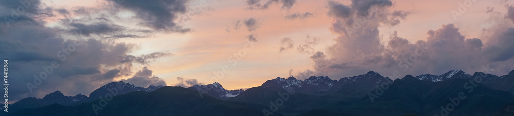 Panorama of mountains and colorful clouds at sunset..Sky panorama above the towering peaks of high mountains.