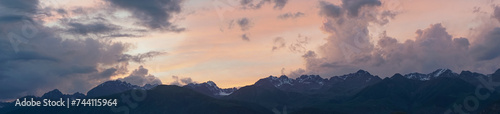 Panorama of mountains and colorful clouds at sunset..Sky panorama above the towering peaks of high mountains.